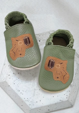 Śliczne kapcie barefoot z włoskiej skóry z oddychającą, zamszową podeszwą w kolorze khaki zielonym w motywem modnej kapibary. Piękne i lekkie. Propozycja na pierwsze buciki. Super do żłobka i przedszkola, Buciki oddychające na potliwe stópki.