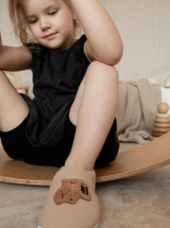 Piękne kapcie barefoot z włoskiej skóry w kolorze beżowym z motywem kapibary, z kauczukową podeszwą. Idealne kapcie do żłóbka i przedszkola ponieważ są super antypoślizgowe